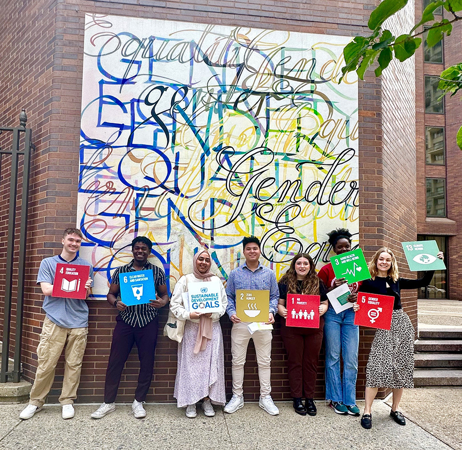 A group of people holding signs in front of a mural. Credit Global Philadelphia Association