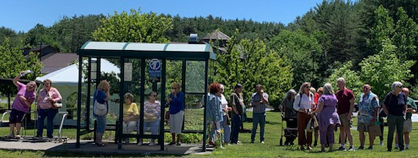 A big group at a bus shelter with trees in background. Credit: Mpact