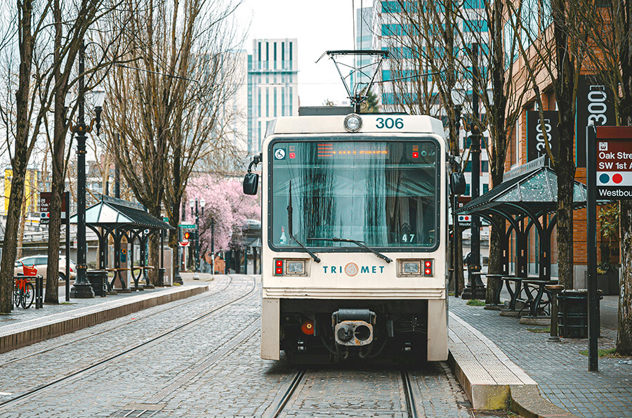 MAX train in downtown Portland, OR, with flowering trees visible down the street. Photo credit Brett Sayles