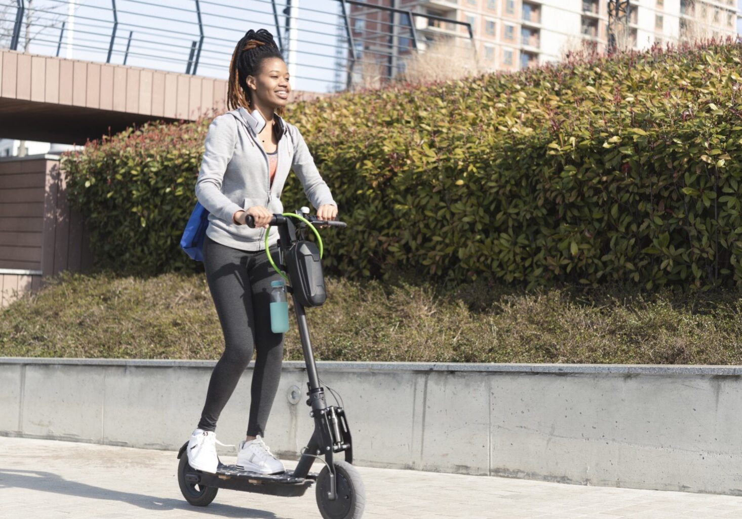 Portrait of a young African American woman riding an electric push scooter through the city